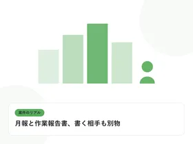 PCの前に座る人物のシルエットと現場のビル群を表し、案件のリアルを表したイラストに「月報と作業報告書、書く相手も別物」という見出しを添えたアイキャッチ画像